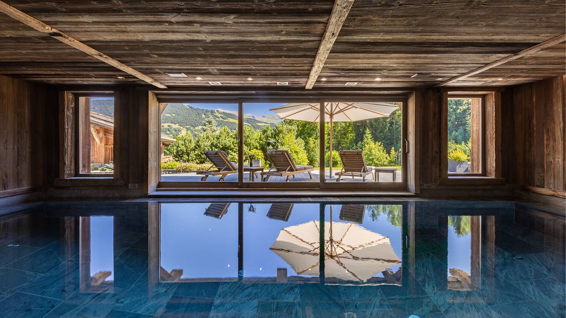 indoor pool with outdoor sunbeds and umbrella