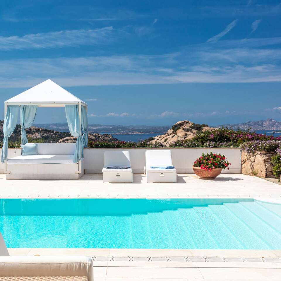 infinity swimming pool with covered sunbeds and sea view