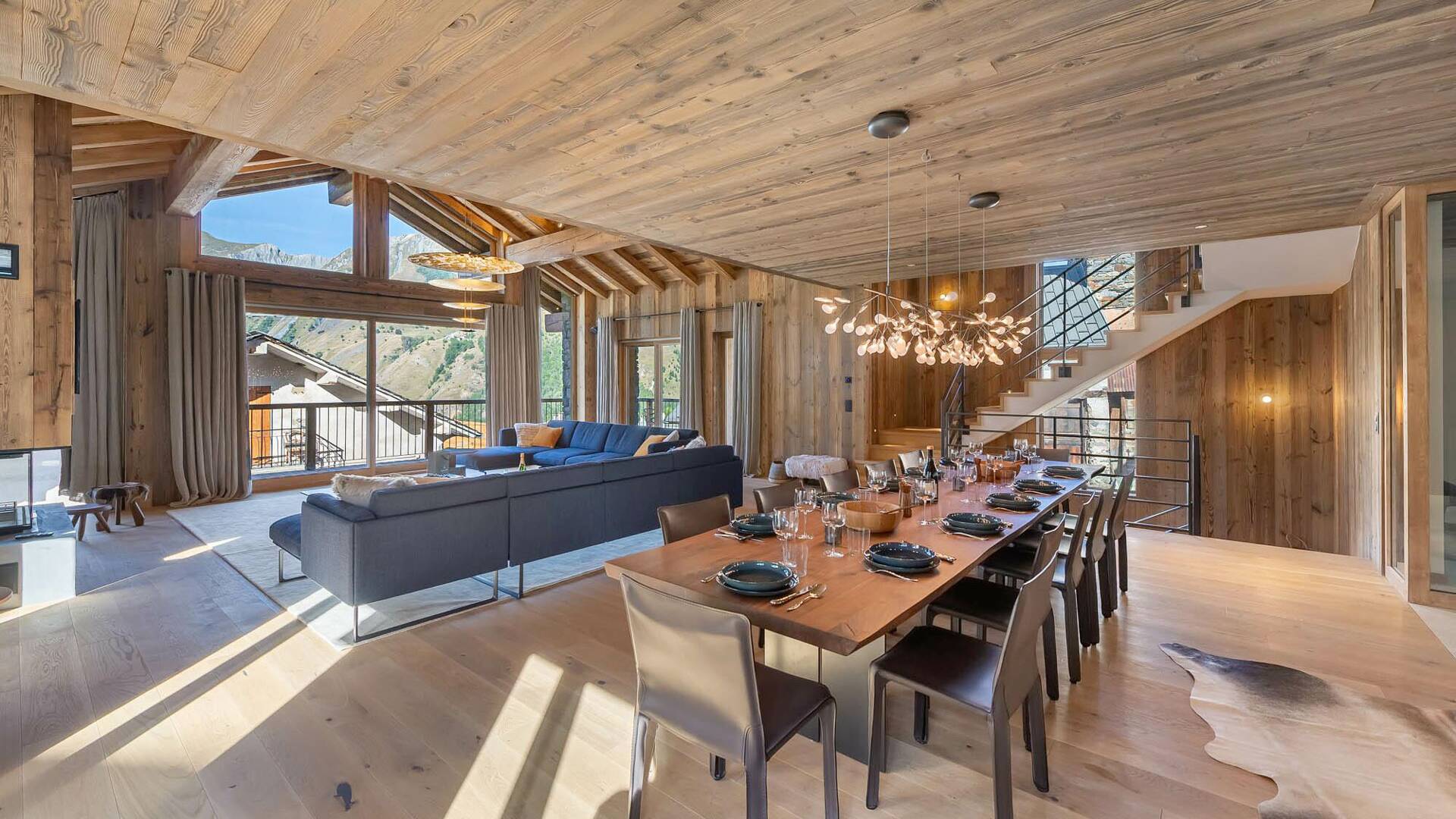 spacious living room with dining table, large window and balcony with stunning Alps views