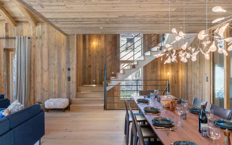 spacious living room with dining table, large window and balcony with stunning Alps views