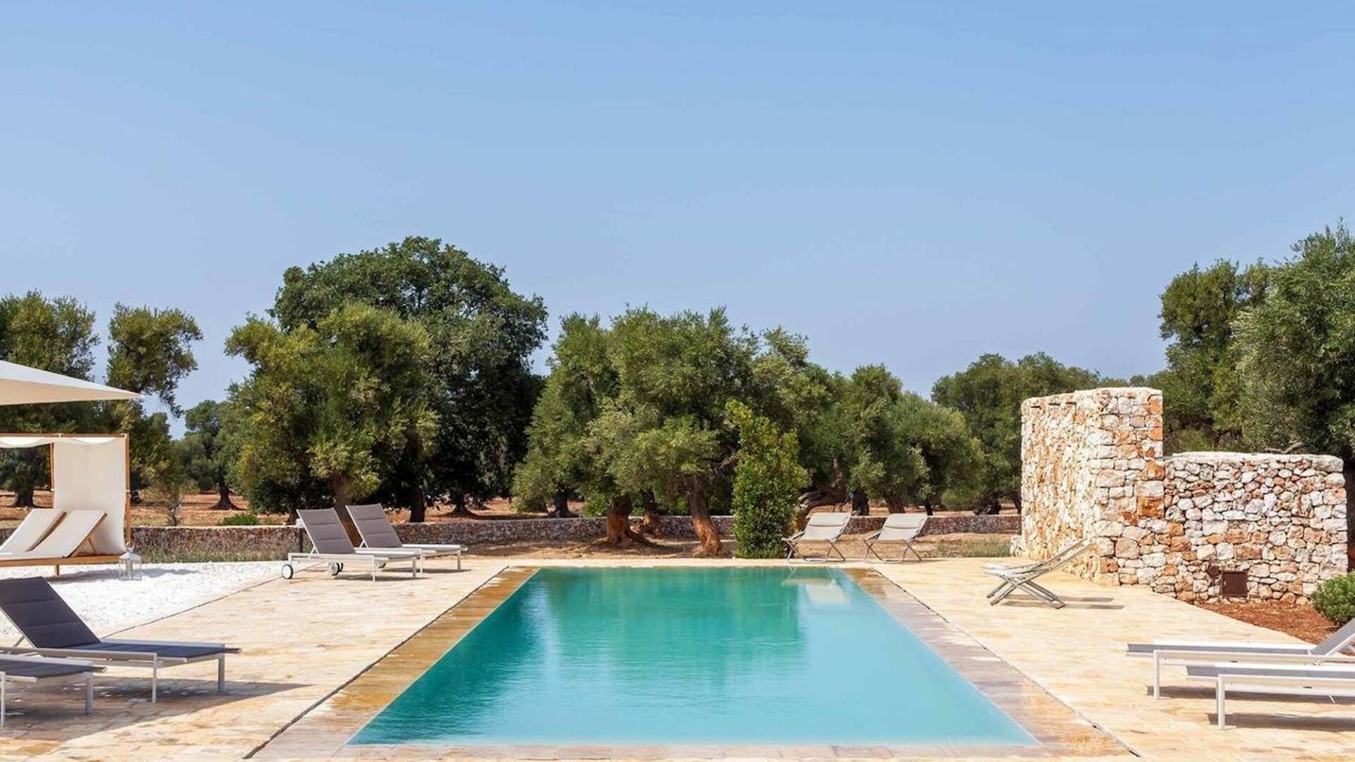 outdoor lounge area with pool and sunbeds