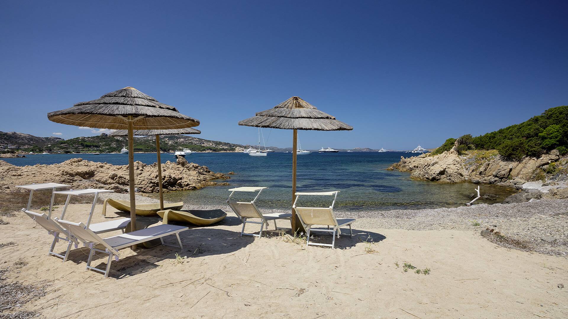 sandy beach in front of the villa equipped with sun loungers and umbrellas 