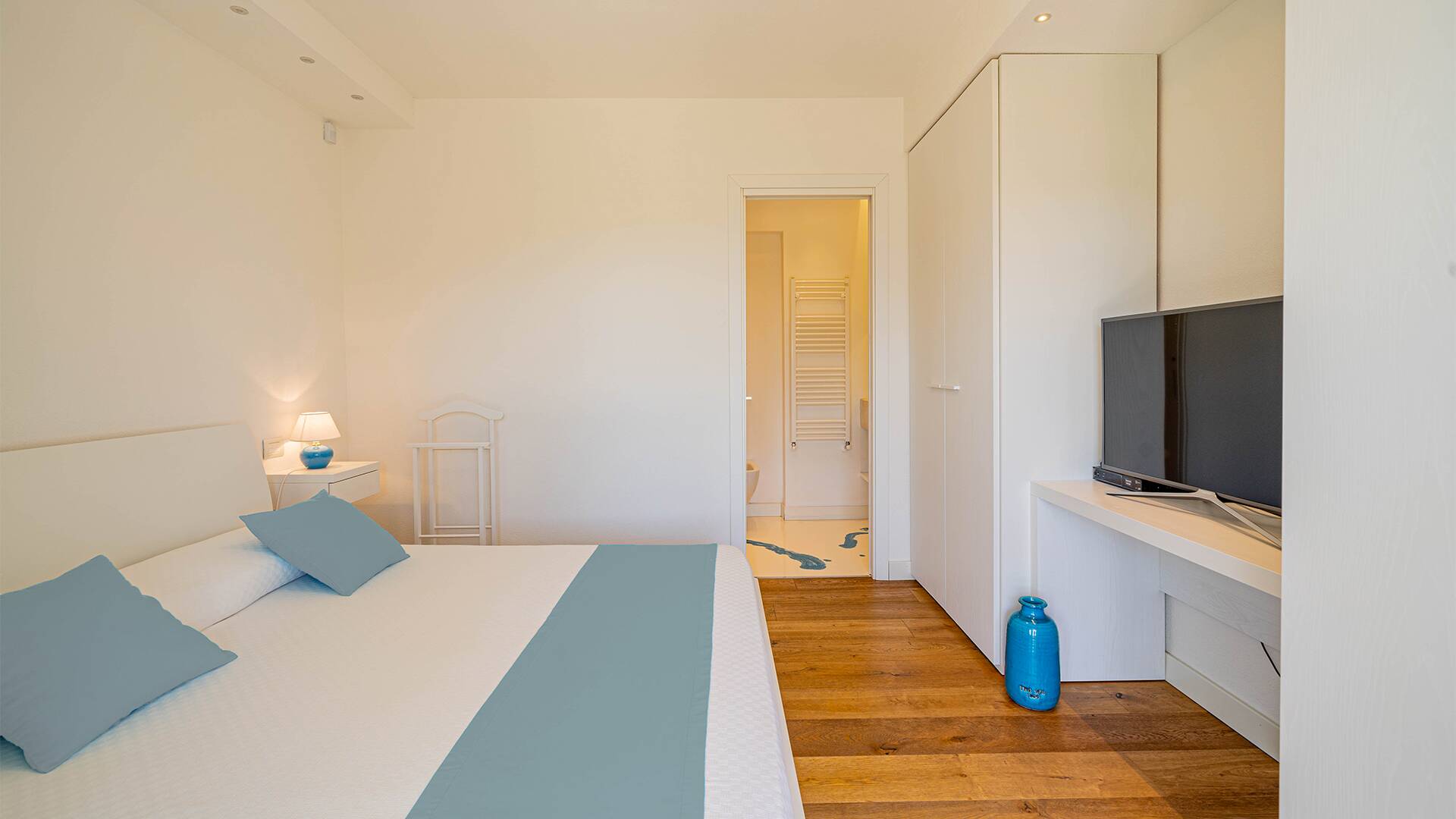 blue double bedroom with TV and en suite bathroom