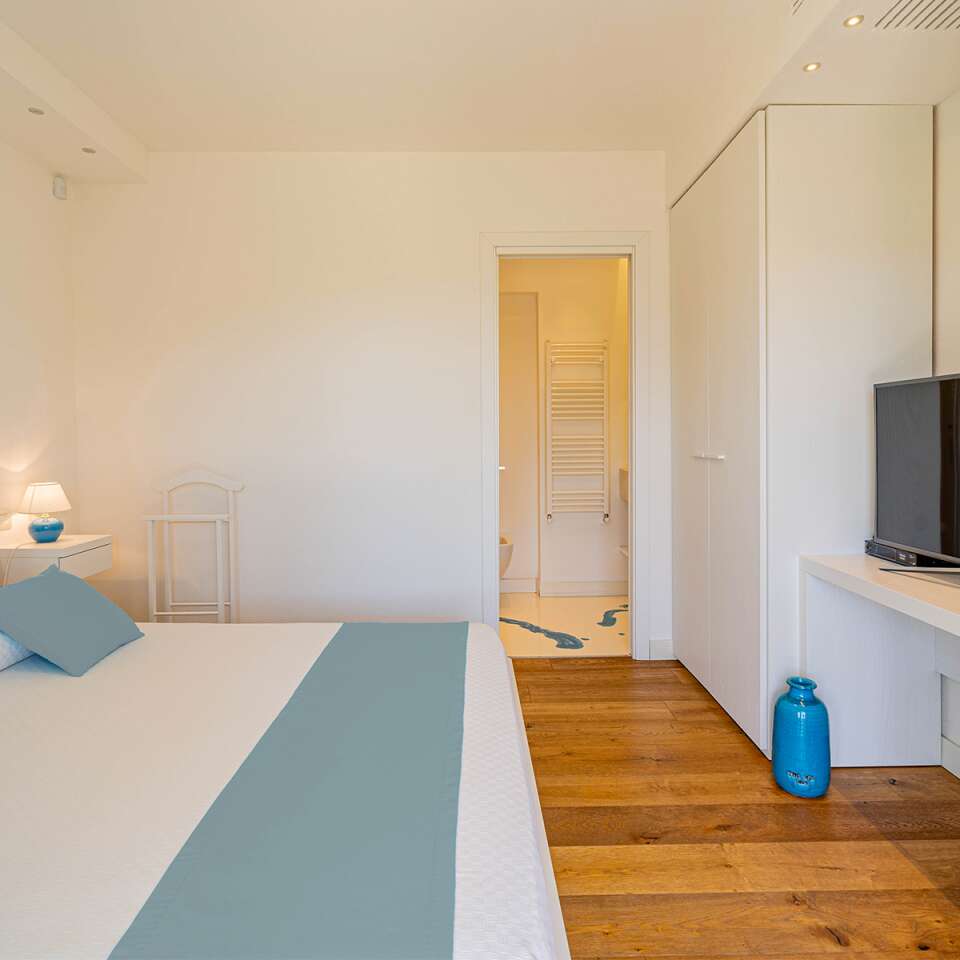 blue double bedroom with TV and en suite bathroom