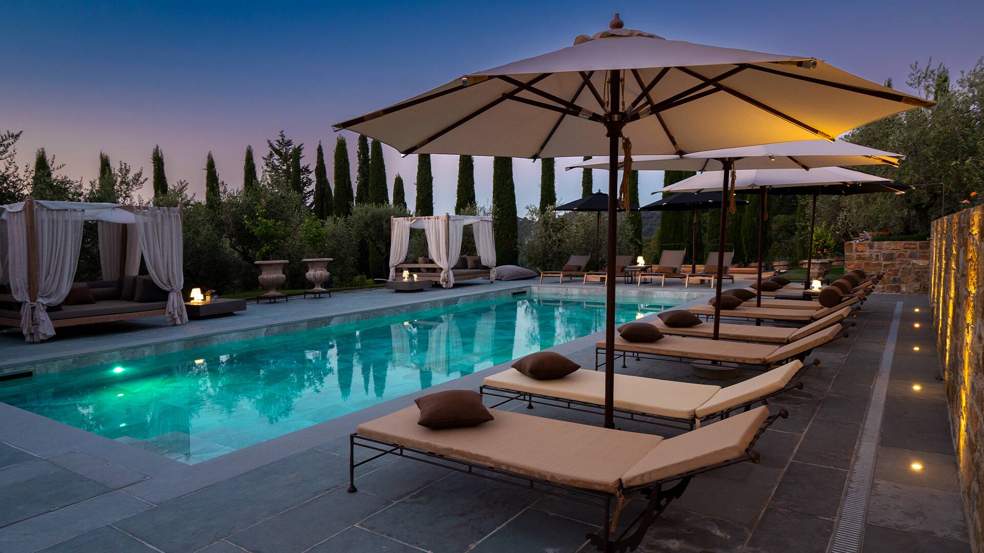 swimming pool with sunbathing area by night